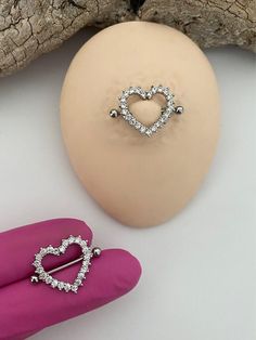 a heart shaped pin sitting on top of a piece of wood next to a pink glove