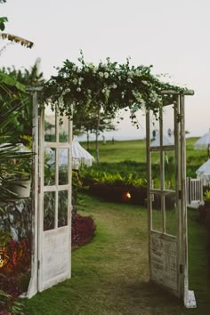 an outdoor wedding ceremony setup with flowers and greenery on the grass, in front of a white gazebo