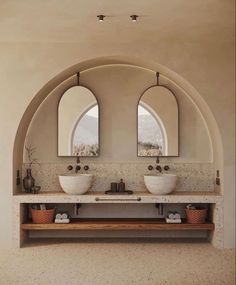 a bathroom with two sinks and three mirrors on the wall next to each other in front of an arched window