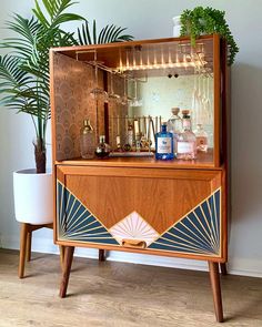 a wooden cabinet with an art deco design on the front and sides, along with a potted plant