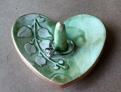 a green heart shaped dish with a ring on it