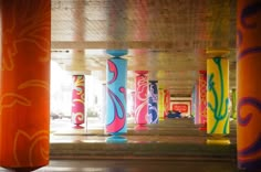 colorful columns are lined up in the middle of an empty parking garage with graffiti on them