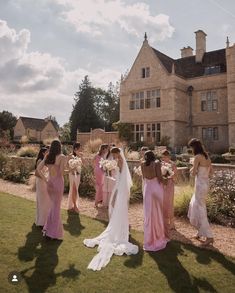 a group of bridesmaids standing in front of a large house with their backs to the camera