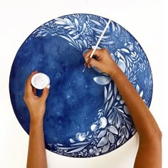 a person painting on a blue plate with white paint