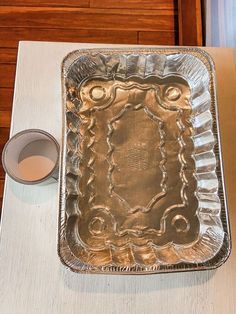 a metal pan sitting on top of a table next to a cup and saucer