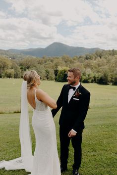 a bride and groom standing in the grass