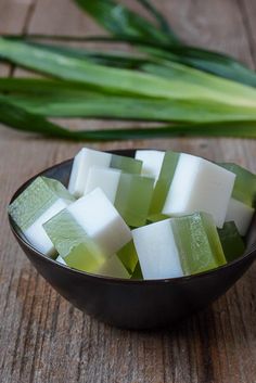 green and white cubes in a black bowl on a wooden table next to tulips