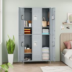 a room with a bed and a large white locker next to a plant on the floor