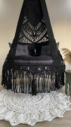 a black bed with fringes and pillows on top of a white doily rug