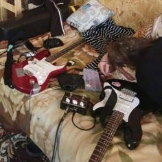 a person laying on top of a bed with guitars