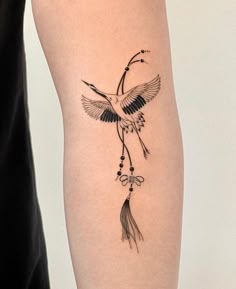 a woman's leg with a tattoo on it that has a bird and beads hanging from it