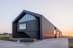 a black building with large windows on the top floor and an open area in front of it