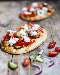 two flatbread pizzas with tomatoes, cucumbers, and chicken on them