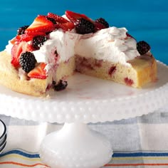 a cake with berries and whipped cream is on a plate next to a bowl of lemons