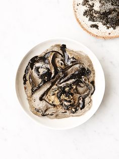 a white bowl filled with ice cream next to a slice of bread on top of a table