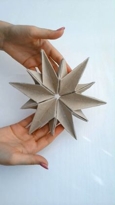 two hands are holding an origami star