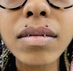 a close up of a person with piercings on her nose and glasses over their eyes