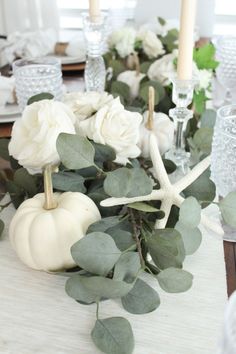 the table is set with white pumpkins and greenery