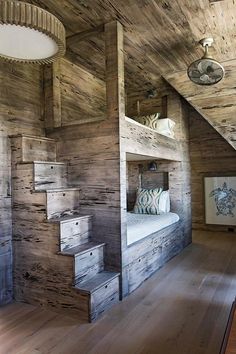 a bedroom with wooden walls and stairs leading up to the loft bed in the room