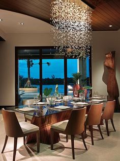 a dining room table with chairs and a chandelier hanging from it's ceiling