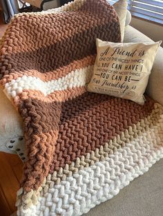 a brown and white blanket sitting on top of a couch next to a throw pillow