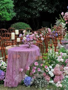 there is a table with a purple cloth on it surrounded by chairs and tables covered in flowers