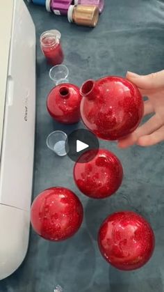 someone is making red ornaments out of plastic balls