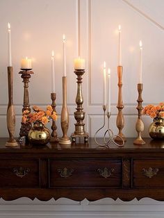 a table topped with lots of candles and vases filled with orange flowers on top of it