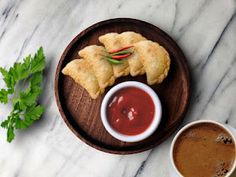 two cups of coffee sit next to pastries on a wooden plate with sauces