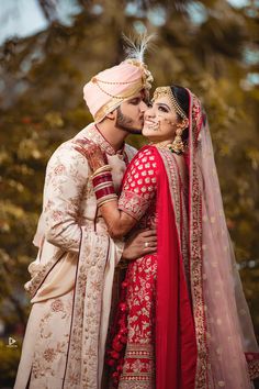 a bride and groom pose for a wedding photo in front of some trees with their heads together