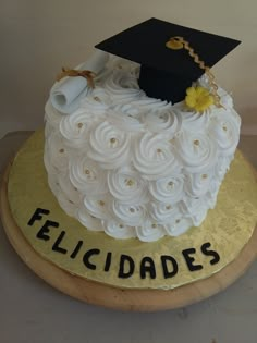 a cake that is decorated with white icing and black graduation cap on top of it