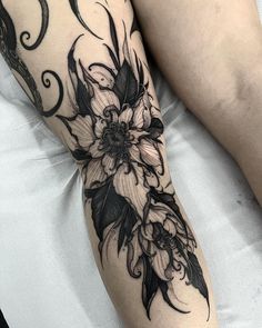 a woman's leg with black and white flowers on it, while she is laying down