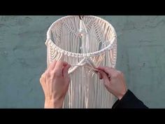 two hands are working on a white macrame