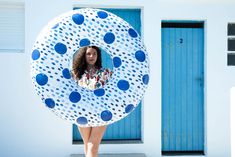 a woman standing in front of a blue and white building holding a large round object