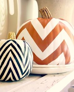 three painted pumpkins sitting on top of a white shelf