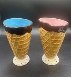 two ice cream cones sitting next to each other on top of a black countertop