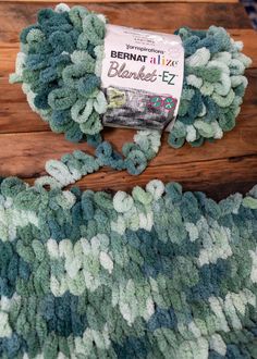 a close up of a rug on a wooden floor with yarn in it and a package of fabric next to it