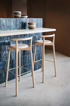 two stools and a table in front of a blue tile wall with bowls on it