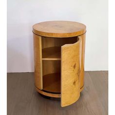 a round wooden table with an open door on the top and bottom section, sitting on a hard wood floor