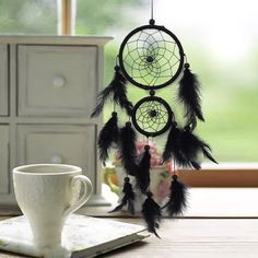 a coffee cup sitting on top of a table next to a black and white dream catcher