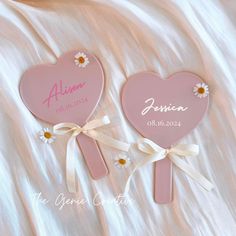 two pink hearts with daisies on them sitting next to each other in front of a white blanket