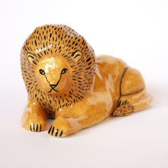 a ceramic lion figurine laying down on the ground