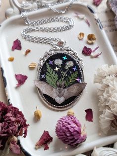 This gorgeous cameo necklace is handmade by me and one of a kind. Necklace is made with a silver cameo that has black resin inside to give a midnight scenery look! Encased in the resin is a faux bat, dried fern leaves, dried pressed flowers and holographic stars. Necklace chain is approximately 18". If you prefer a different length, send me a message and I'll adjust it for you at no additional charge! Cameo is about 1.5" x 1". Ready to ship! Instagram: @whimsy.folk Midnight Scenery, Goth Flowers, Dried Fern, Stars Necklace, Flowers Resin, Dried Pressed Flowers, Jewelry Goth, Fern Leaves, Dried And Pressed Flowers