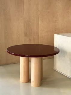 a round table with two wooden legs in front of a wood paneled wall and floor