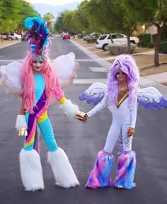 two women dressed in costumes are walking down the street while one holds her hand out