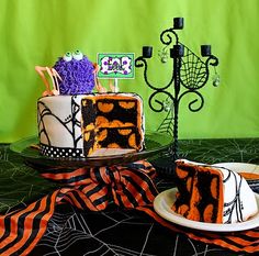 two cakes decorated with halloween decorations on top of a black tablecloth and green backdrop