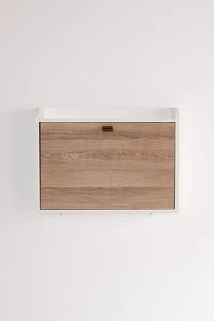 a white wall with a wooden cabinet on it's side and a light brown drawer in the middle