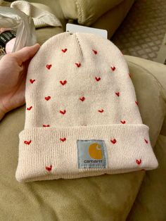 someone is holding a beanie hat with hearts on it and the label says comfort