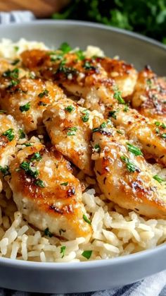 a white bowl filled with rice covered in chicken and parsley on top of it