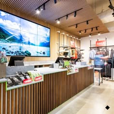 the inside of a clothing store with people shopping in front of large televisions on the wall